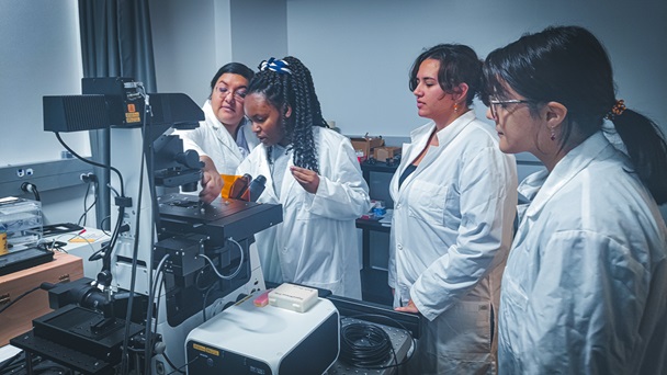 faculty and students in Biophysics lab checking specimen in microscope